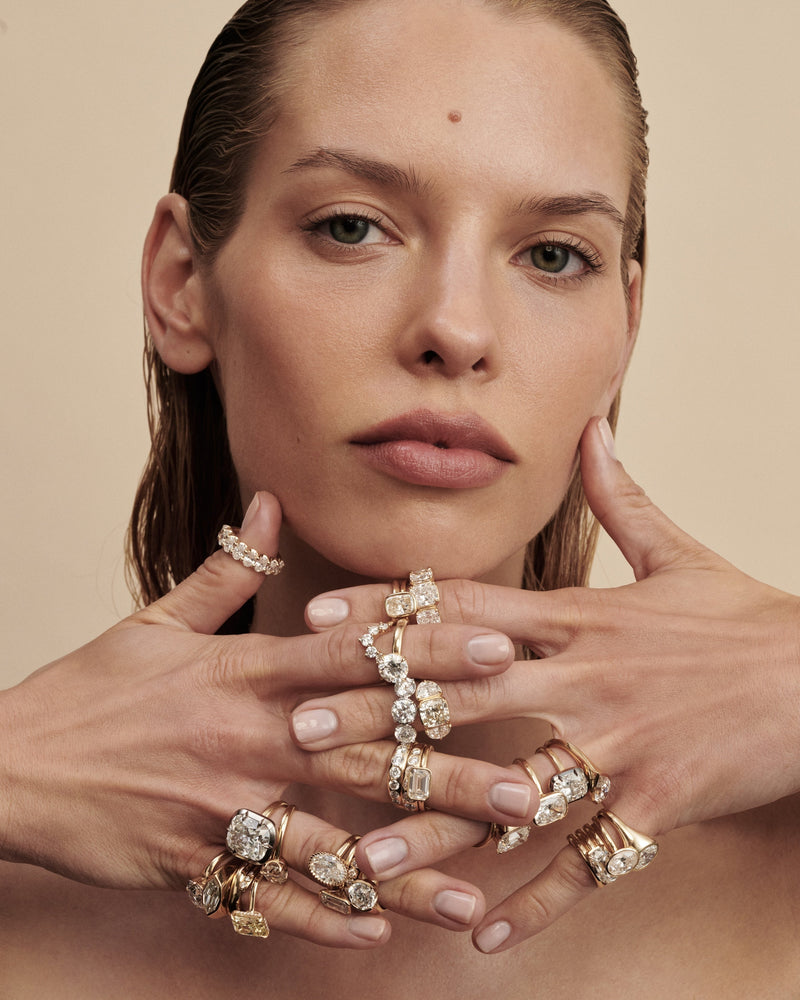 A close-up portrait of a woman with her hands crossed in front of her face, wearing all of Lindelli's most popular engagement ring set with diamonds 